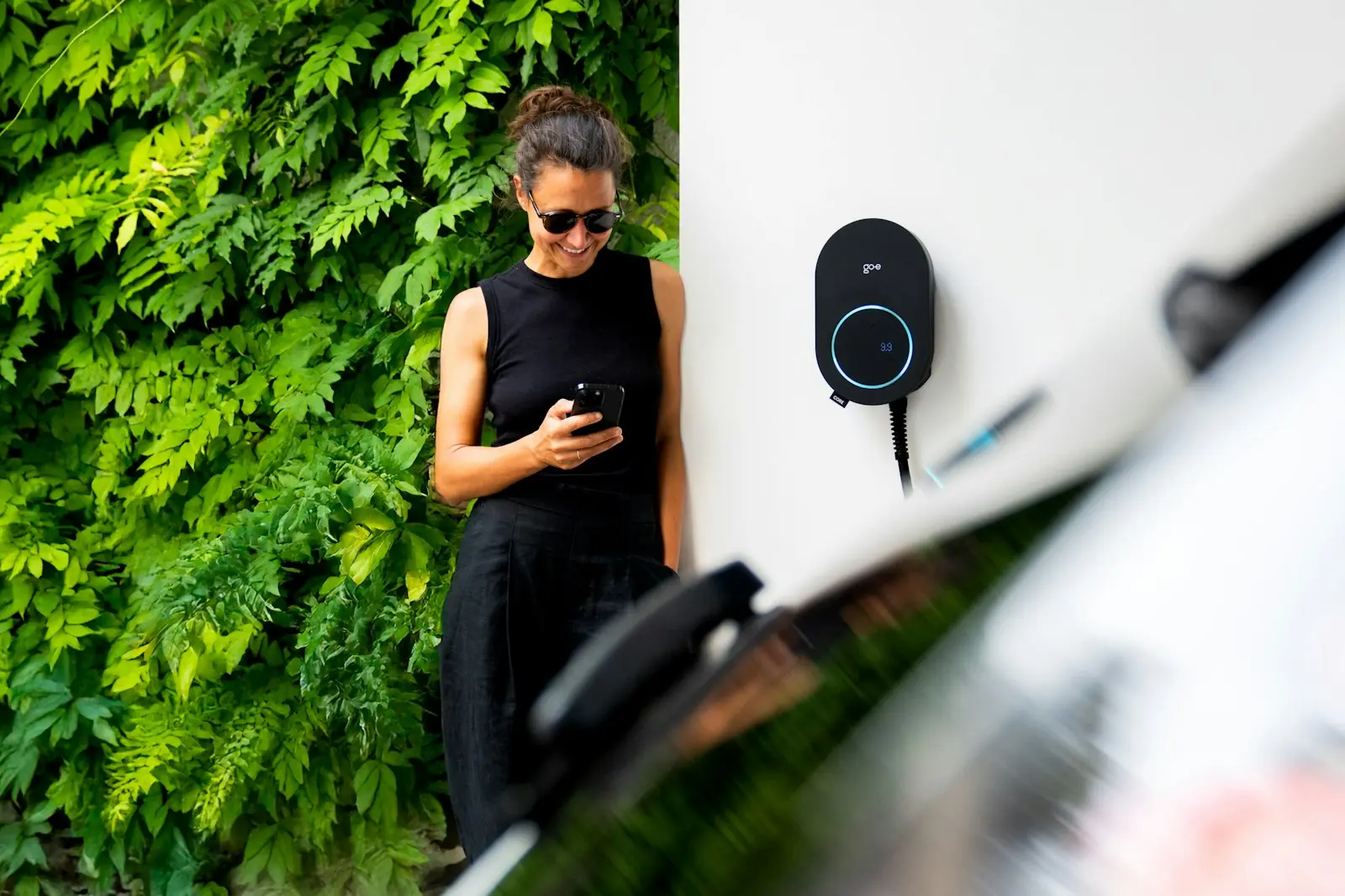 Vrouw bekijkt haar laadsessie in de Amfy-app naast haar laadpaal