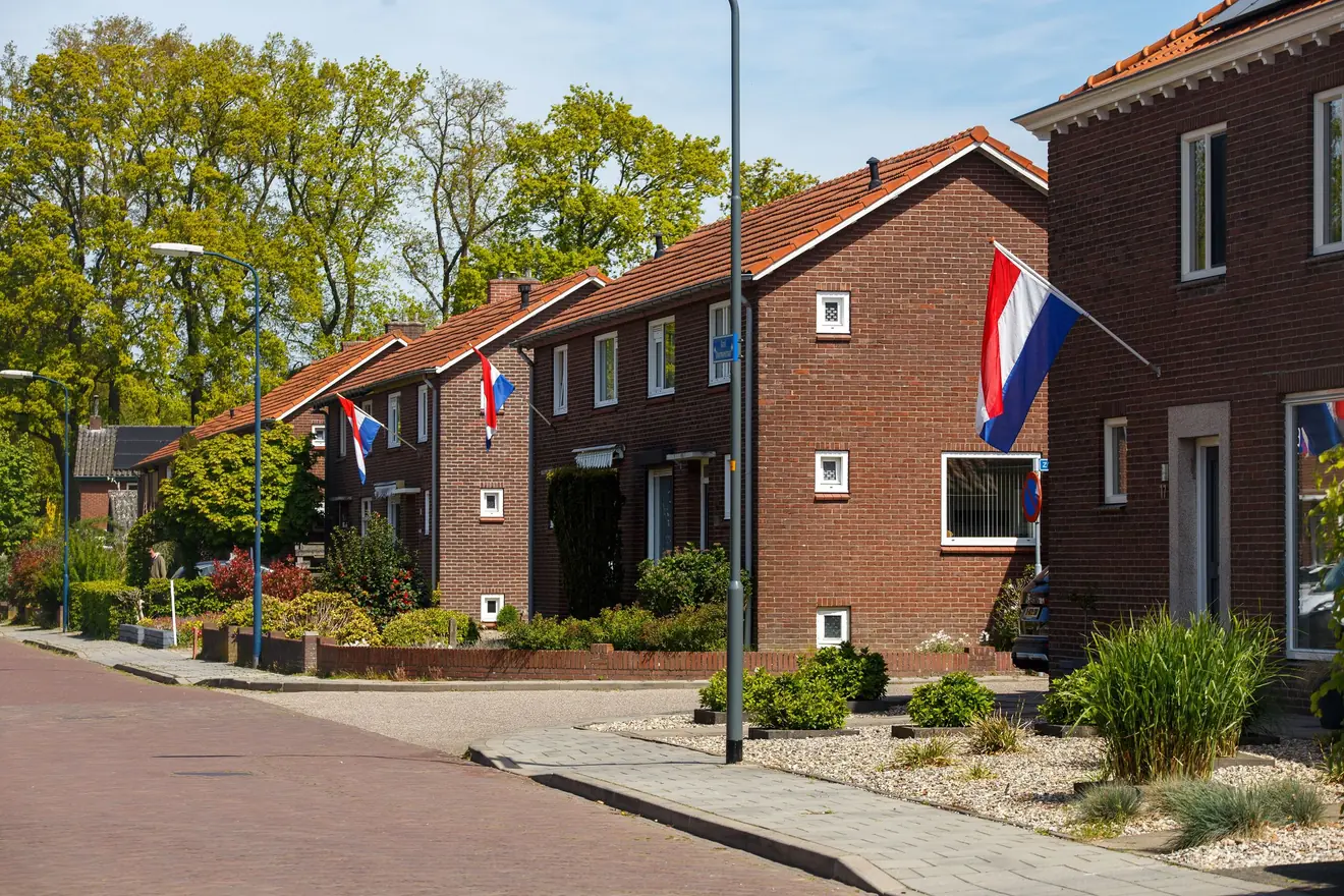 Straat met bakstenen rijtjeshuizen in Doetinchem, met Nederlandse vlaggen aan de gevels