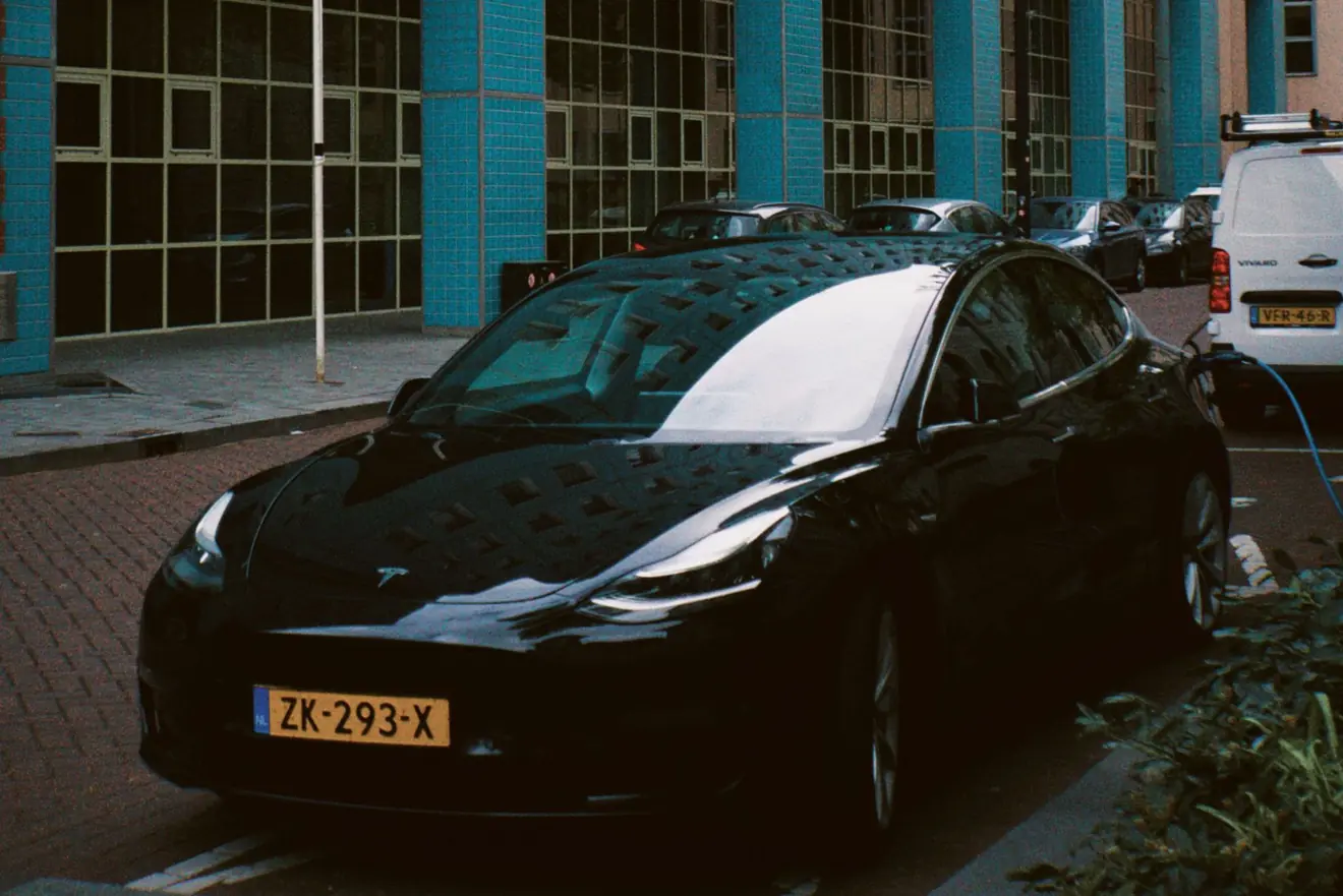 Zwarte elektrische auto met een Nederlands kenteken, geparkeerd in een straat in Rotterdam